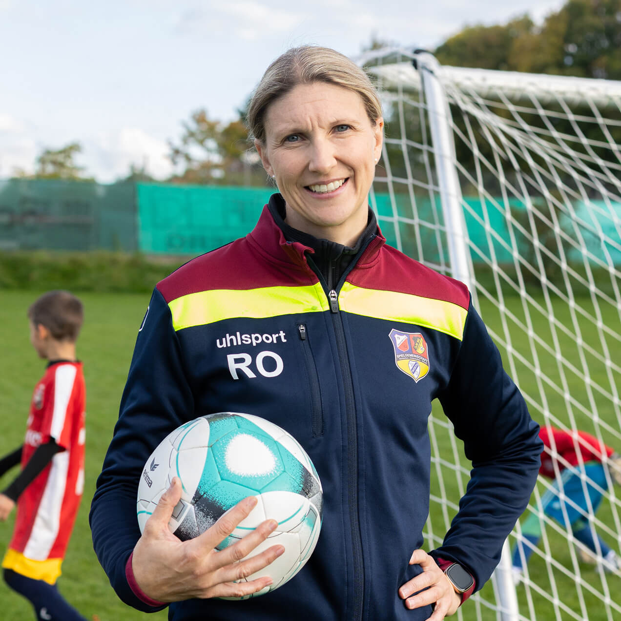 Frau im Fußballtrikot mit Fußball vor einem Tor